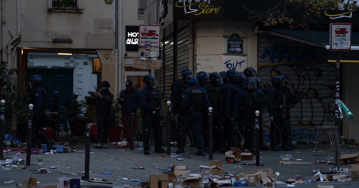 Riot police stand among debris outside a looted shop on Boulevard Voltaire in Paris during the France riots