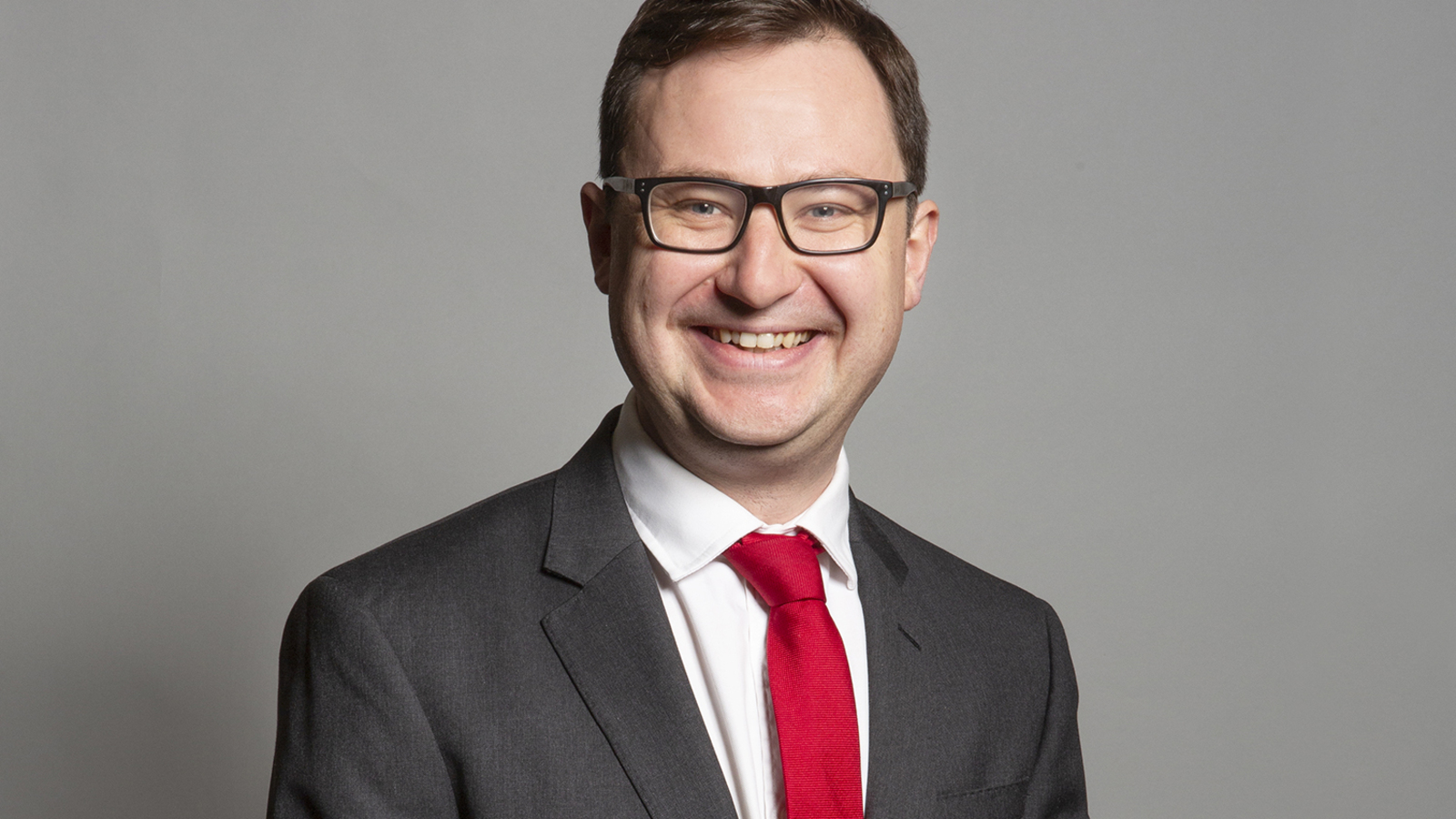 Alex Norris MP, Lord Chancellor and Justice Secretary, smiling in a dark suit and red tie